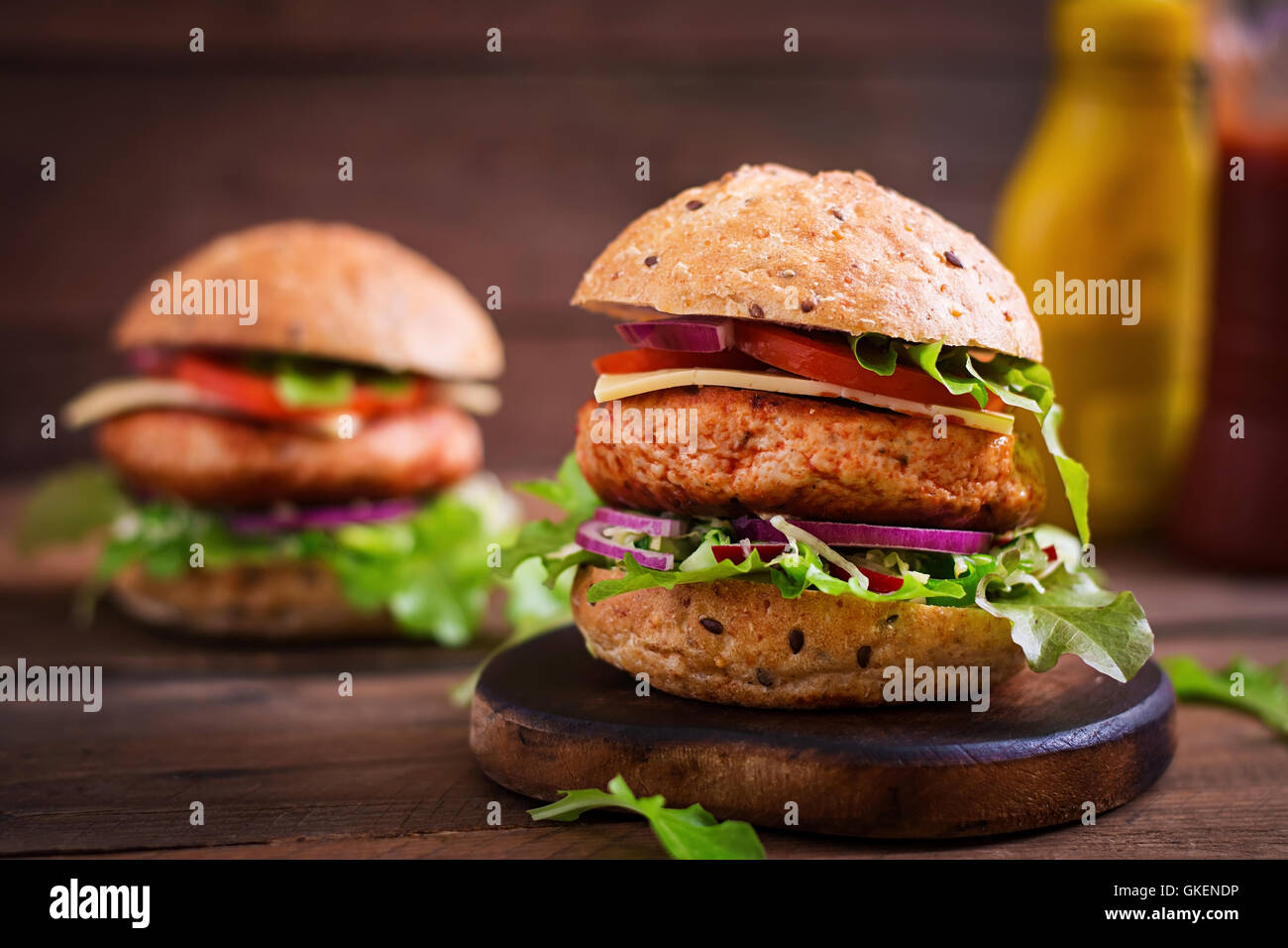 Big Sandwich - Hamburger mit saftige Hähnchen Burger, Käse, Tomaten und roten Zwiebeln auf hölzernen Hintergrund Stockfoto