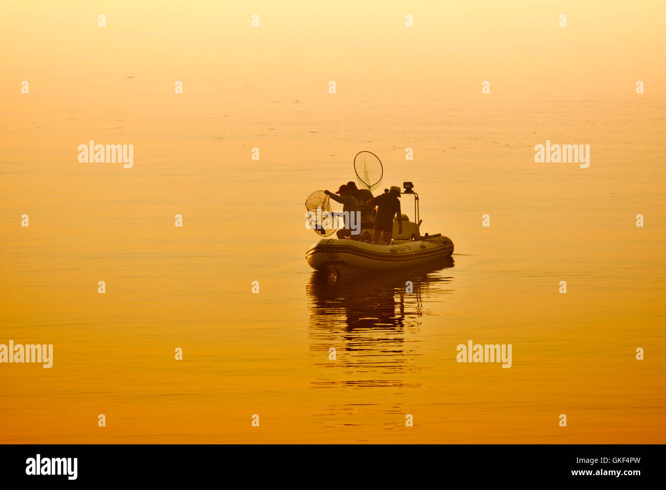 Fischer im Meer bei Sonnenuntergang auf dem Boot PVC-Scheck Stockfoto