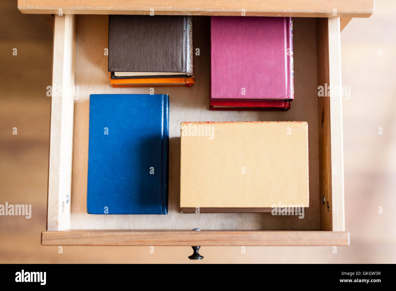 Draufsicht auf mehrere kleine Bücher im offenen Schublade des Nachttisch Stockfoto