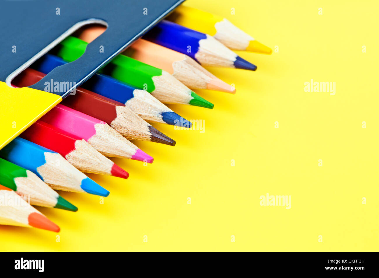 Schachtel mit Buntstiften auf einem gelben Hintergrund. Stockfoto