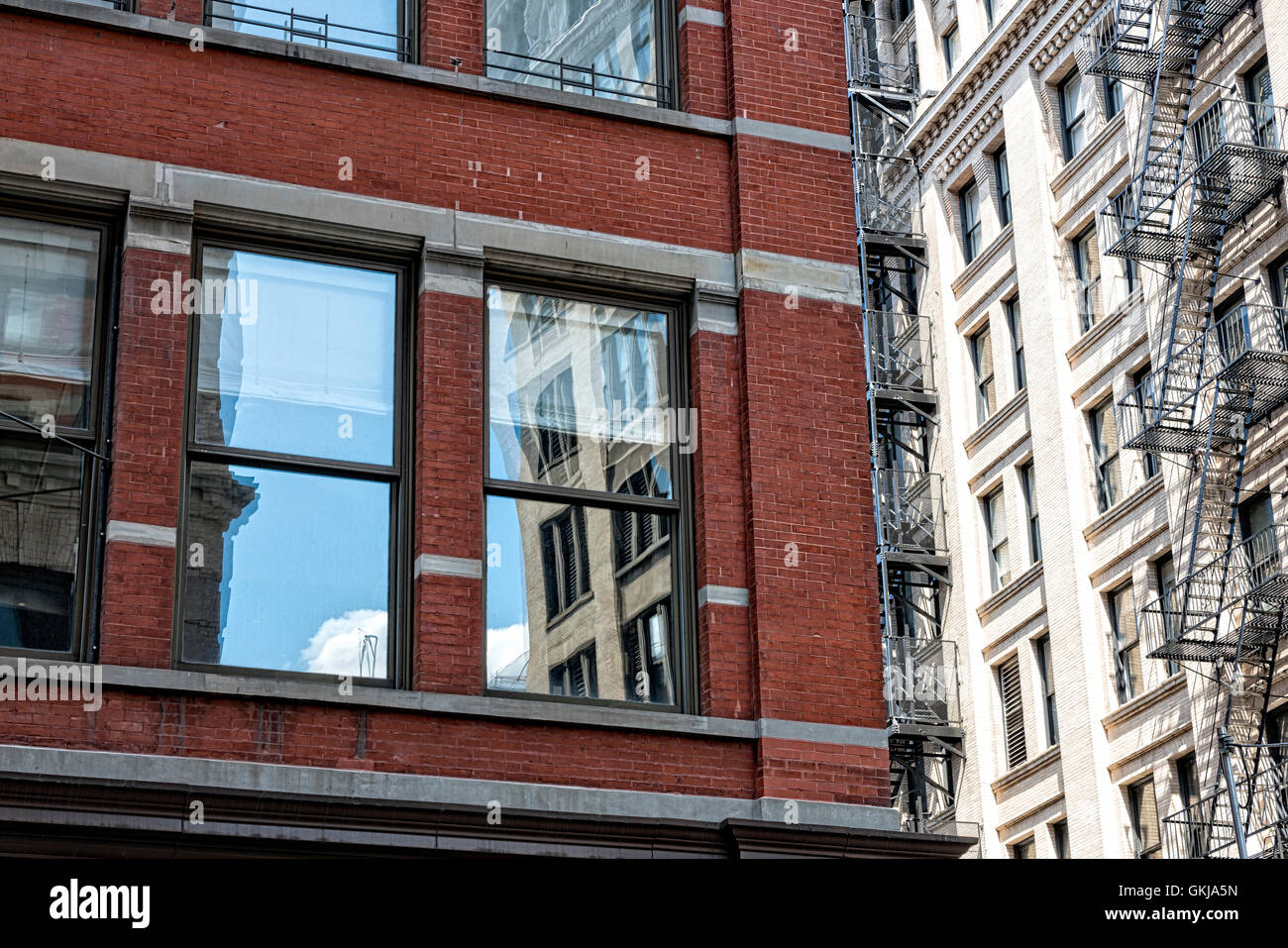 Soho, Manhattan, NYC.  Bauen Reflexionen in die Fenster von einem anderen Gebäude, Cast-Iron-Gebäude auf der rechten Seite. Stockfoto