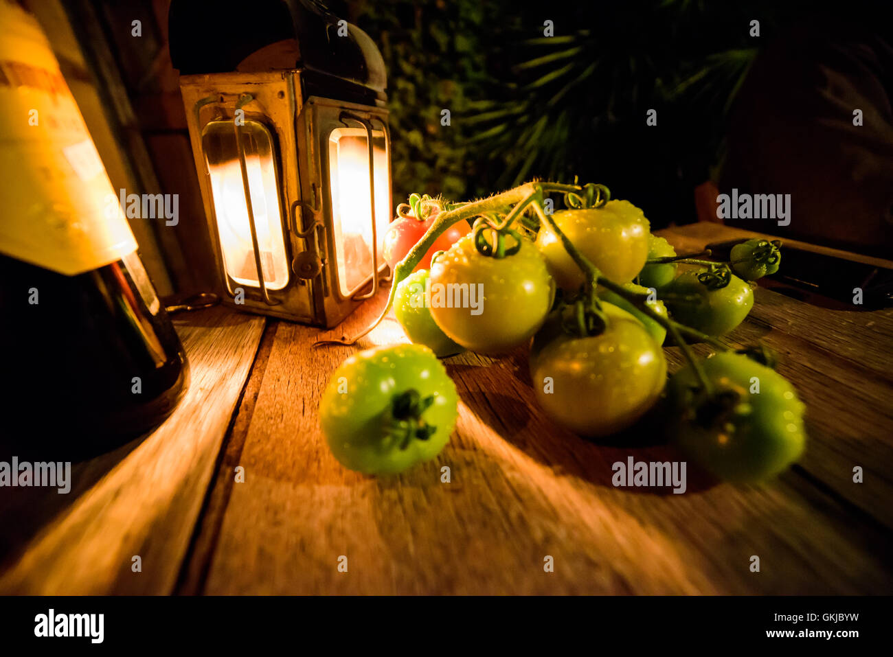 Wein und essen Sie Alfresco frische grüne Tomaten bei Kerzenlicht im Freien Stockfoto