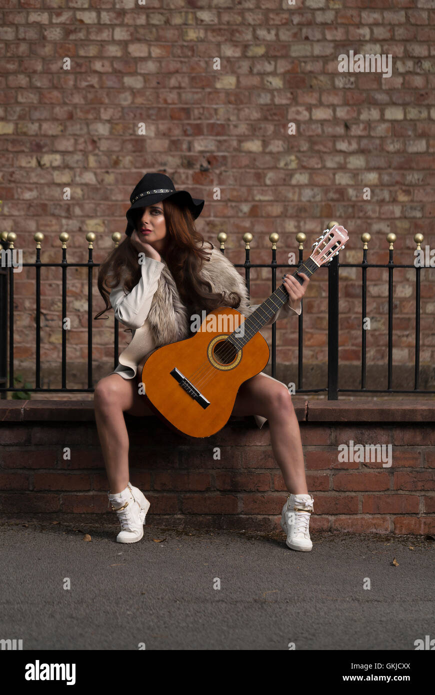 Country-Musik star Performer weiblich, sitzen auf Ziegelwand mit Backstein-Hintergrund Stockfoto