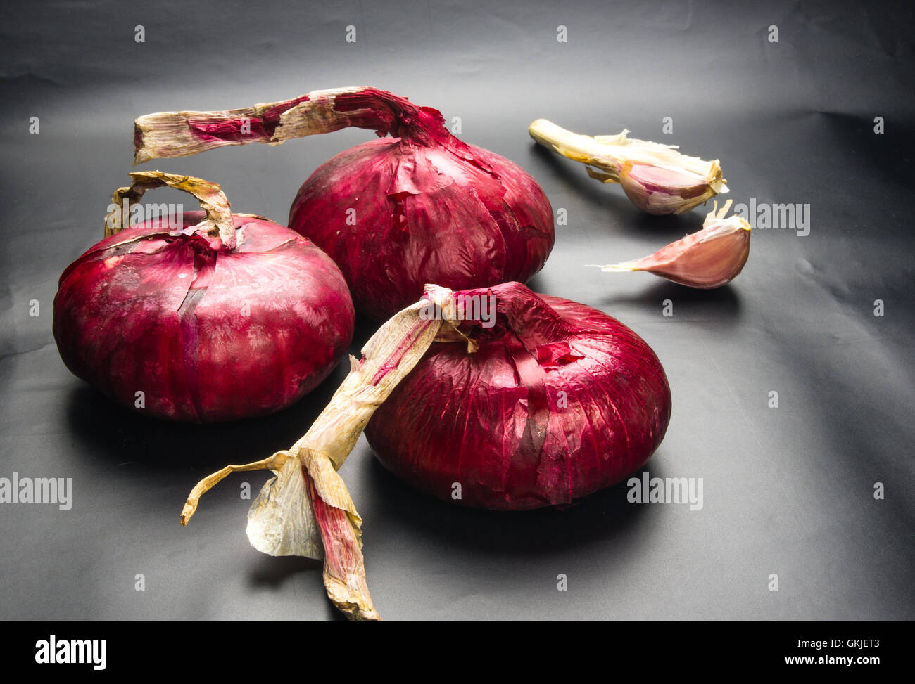 Stillleben - süße lila Krim Zwiebel und Knoblauch auf schwarzem Hintergrund Stockfoto