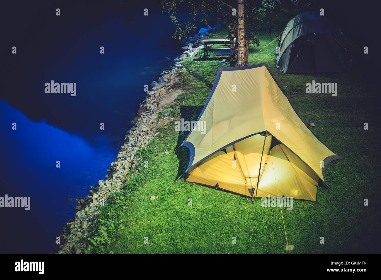 Zelten in der Nacht. Zwei große Zelte auf dem Campingplatz. Campingplatz am Wasser. Stockfoto