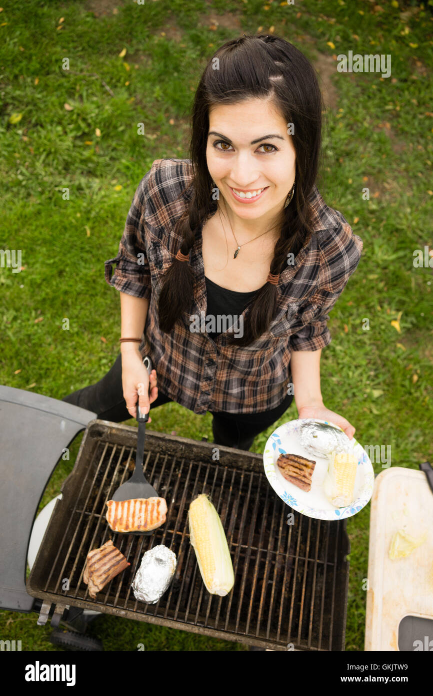 Hübsche Frau lächelnd Grillrost Steaks grillen Garten essen Stockfoto