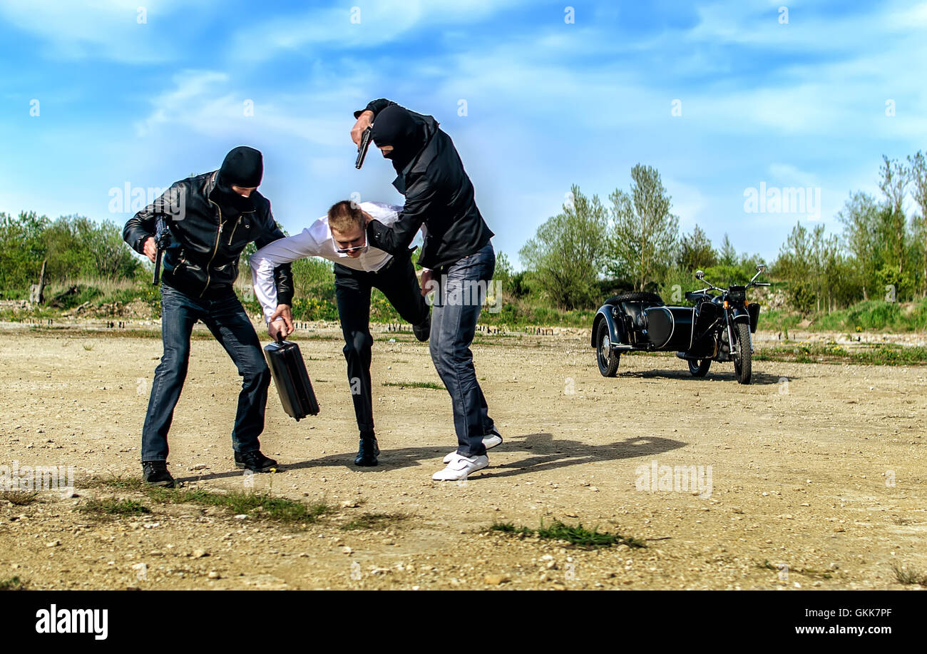 Zwei Banditen entführt einen Geschäftsmann mit einem Koffer Stockfoto