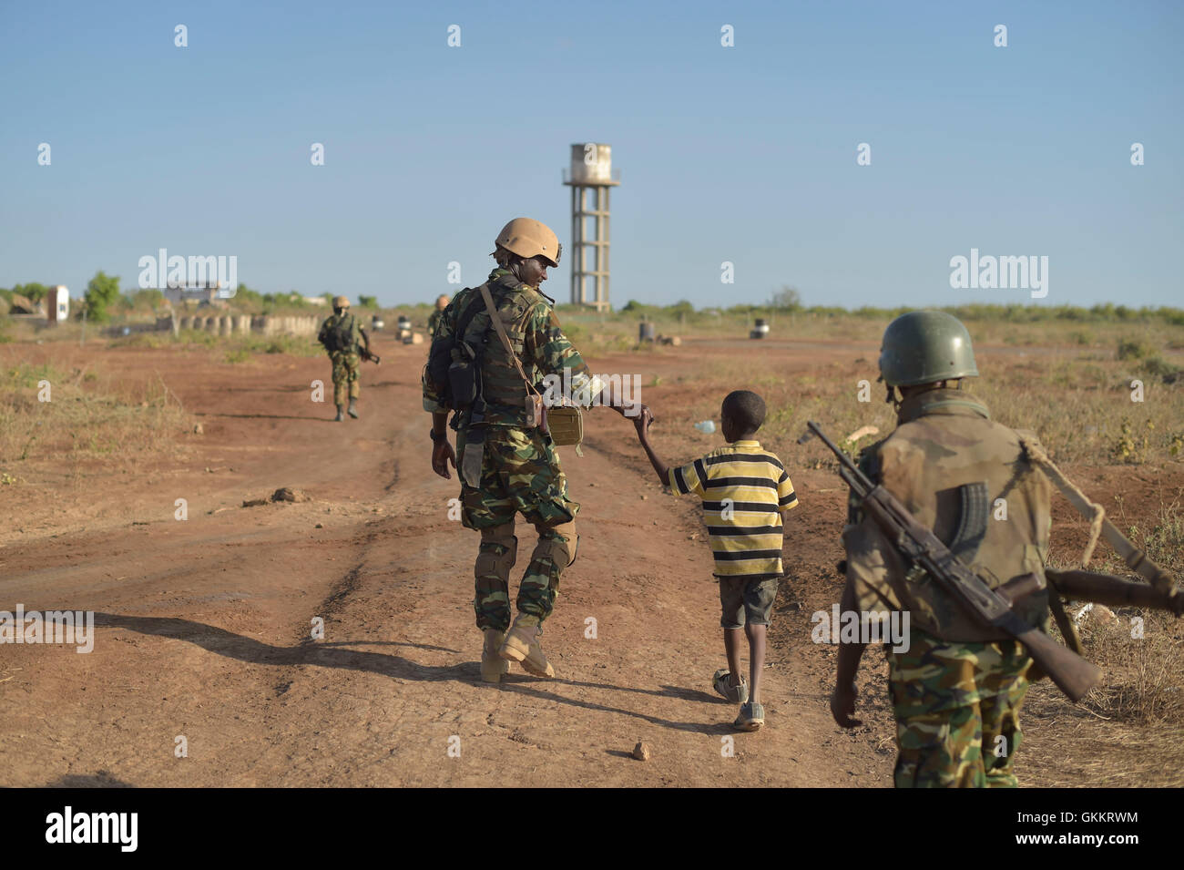 Ein burundischer Soldaten als Teil der Mission der Afrikanischen Union in Somalia, ein kleiner Junge Hand hält in der Nähe der Stadt Mahaday, Somalia, während einer Patrouille. AMISOM Foto / Tobin Jones Stockfoto