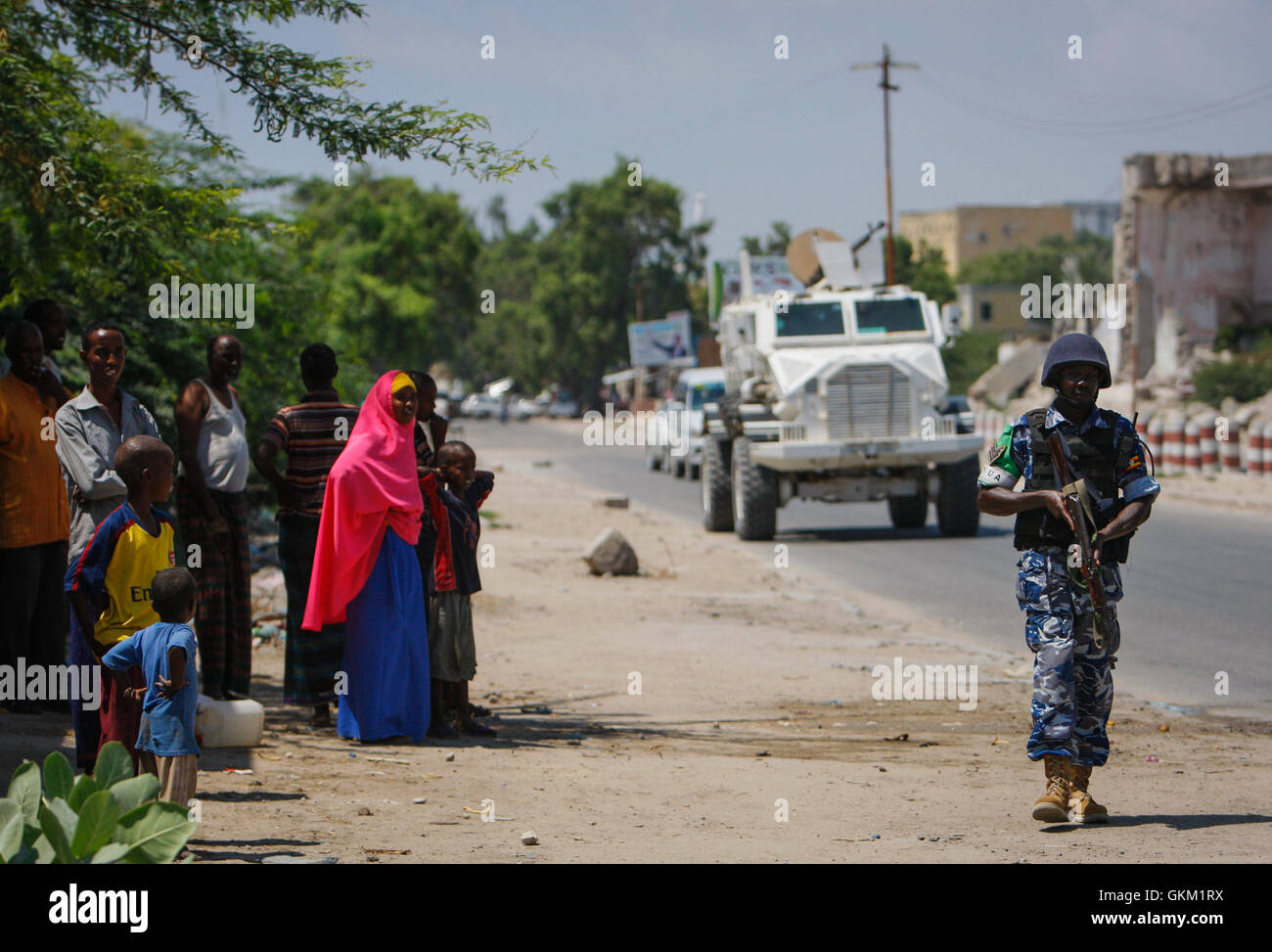 SOMALIA, Mogadischu: Bei einem Handout Foto aufgenommen und veröffentlicht von der hybride Nationen Informationen Support Team 09 November geht somalischen Zivilisten Blick auf als ugandische Polizist als Teil von einem gebildet Polizei Einheit (FPU) mit der Mission der Afrikanischen Union Union in Somalia (AMISOM) vorbei während einer Fuß-Patrouille im Stadtteil Kaa'ran in der somalischen Hauptstadt Mogadischu. Die AMISOM FPUs arbeiten mit ihren Gegenstücken in der somalischen Polizei (SPF) in Beitrag zur Sicherheit in Mogadischu neben der Ausbildung und Betreuung der SPF auf der Polizeiarbeit Techniken und Praktiken. AU-UN IST PH Stockfoto