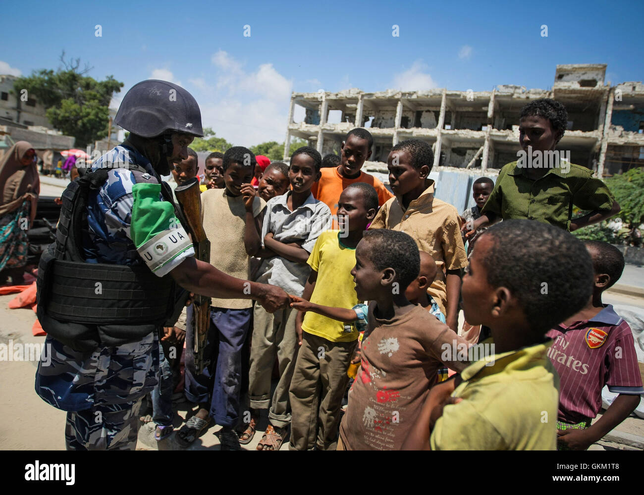 SOMALIA, Mogadischu: In einem Handout Foto aufgenommen und veröffentlicht von der hybride Nationen Informationen Support Team 09 November, schüttelt die ugandische Polizist als Teil von einem gebildet Polizei Einheit (FPU) mit der Mission der Afrikanischen Union Union in Somalia (AMISOM) Hand mit einer Gruppe von somalischen Kinder während einer Fuß-Patrouille im Bezirk Kaa'ran in der somalischen Hauptstadt Mogadischu. Die AMISOM FPUs arbeiten mit ihren Gegenstücken in der somalischen Polizei (SPF) in Beitrag zur Sicherheit in Mogadischu neben der Ausbildung und Betreuung der SPF auf der Polizeiarbeit Techniken und Praktiken. AU-UN Stockfoto