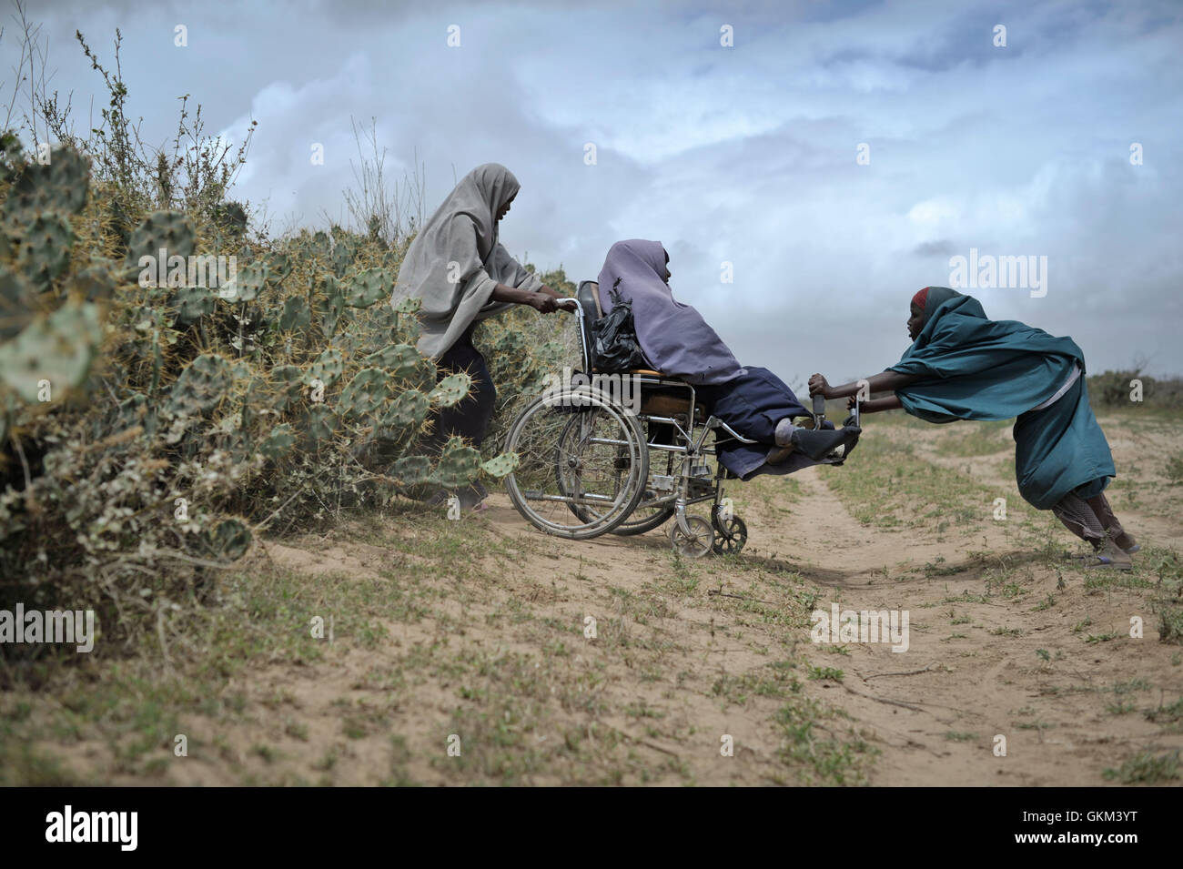 Zwei Frauen unterstützen eine andere am 4. August durch eine Kaktushecke in einem Lebensmittelvertriebszentrum in Afgoye, Somalia, als der Rote Halbmond der USA während des Ramadan Lebensmittel an über 5.000 Binnenvertriebene verteilt. Die AMISOM-Kräfte leisteten Unterstützung. Stockfoto