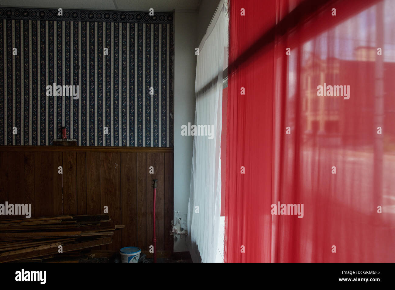 Einen roten und weißen Vorhang in der Fensterbank mit einem gestreiften Tapetendesign Stockfoto