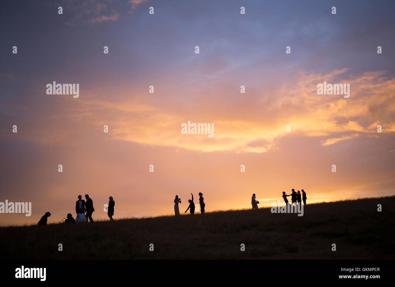Gäste erklimmen einen Hügel um einen Sonnenuntergang zu sehen nach einer Hochzeit in Essex, Ostengland, Großbritannien, 20. August 2016 Stockfoto