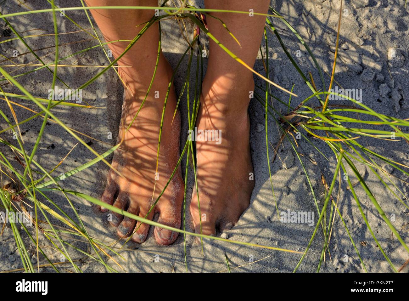 2 gebräunte Füße im Sand an einem Sommertag. Stockfoto