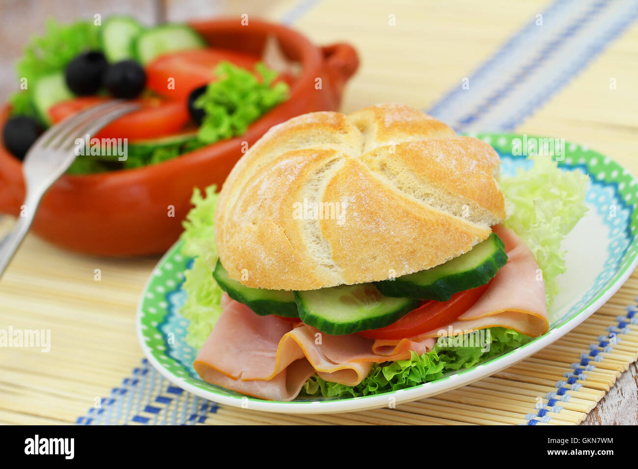 Mittagessen bestehend aus Schinken-Brötchen mit Salat, Tomaten und Gurken und Salat Stockfoto