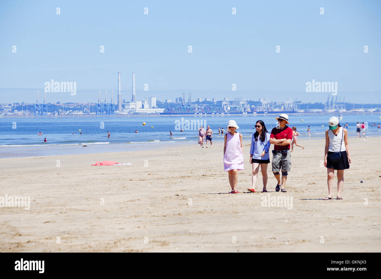 4 Freunde zu Fuß am Strand von Trouville-sur-Mer in der Normandie, mit Le Havre im Hintergrund Stockfoto