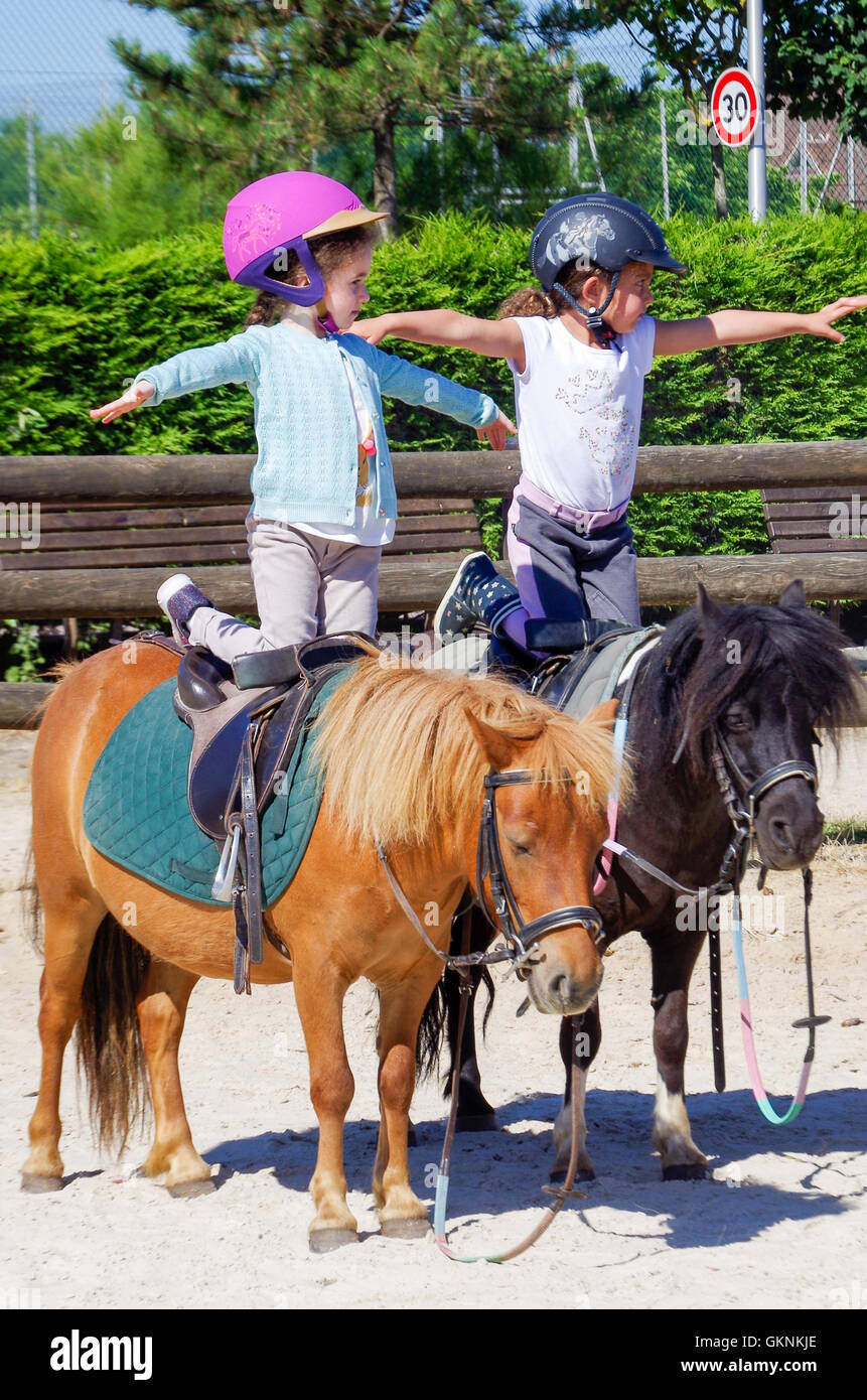 Zwei kleine Mädchen üben Pferdesport Voltigieren und Übungen auf Ponys in Deauville, Frankreich Stockfoto Zwei kleine Mädchen üben Pferdesport Voltigieren und Übungen auf Ponys in Deauville, Frankreich Stockfoto