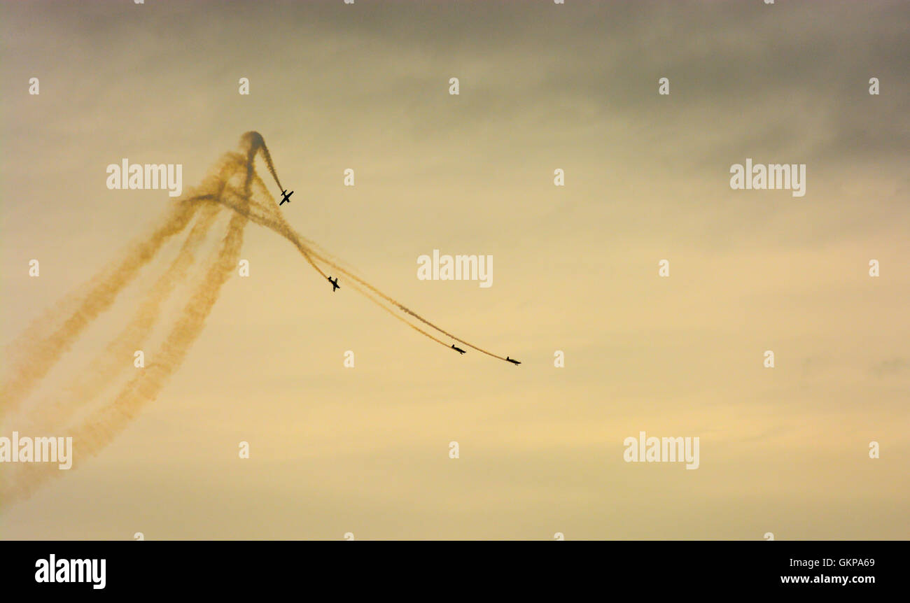 Vier Flugzeuge aus den Blades Aerobatic Air Display Team steigen und fallen, die sich in der Ausbildung mit abschließenden gelben Rauch an der Bournemouth Air Show gegen einen bewölkten Himmel. Stockfoto