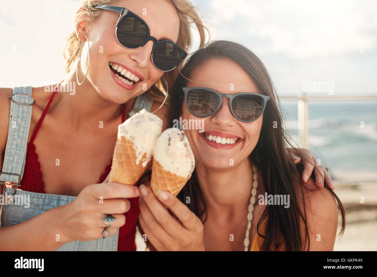 Aufnahme von zwei jungen Freunden Eis zusammen auf einem Sommer-Tag im Freien zu genießen. Nahaufnahme eines fröhlichen weibliche Freunde Essen icecr Stockfoto