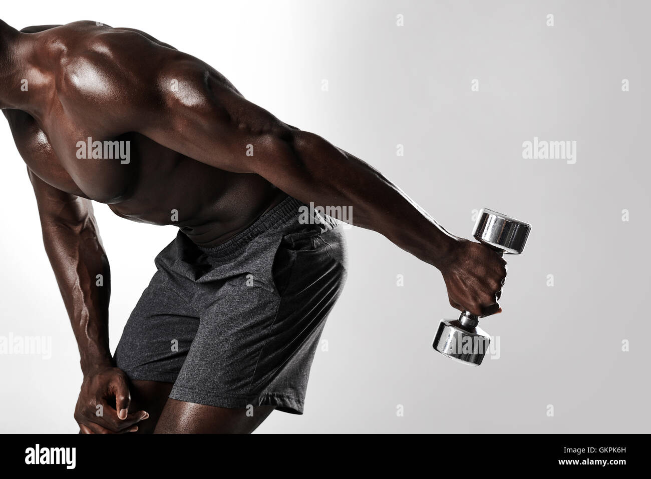 Aufnahme des jungen afrikanischen Mann Hantel Übung für Arme. Muskulösen afrikanischen Fitness-Modell Workout mit Hanteln auf grauen ba Stockfoto