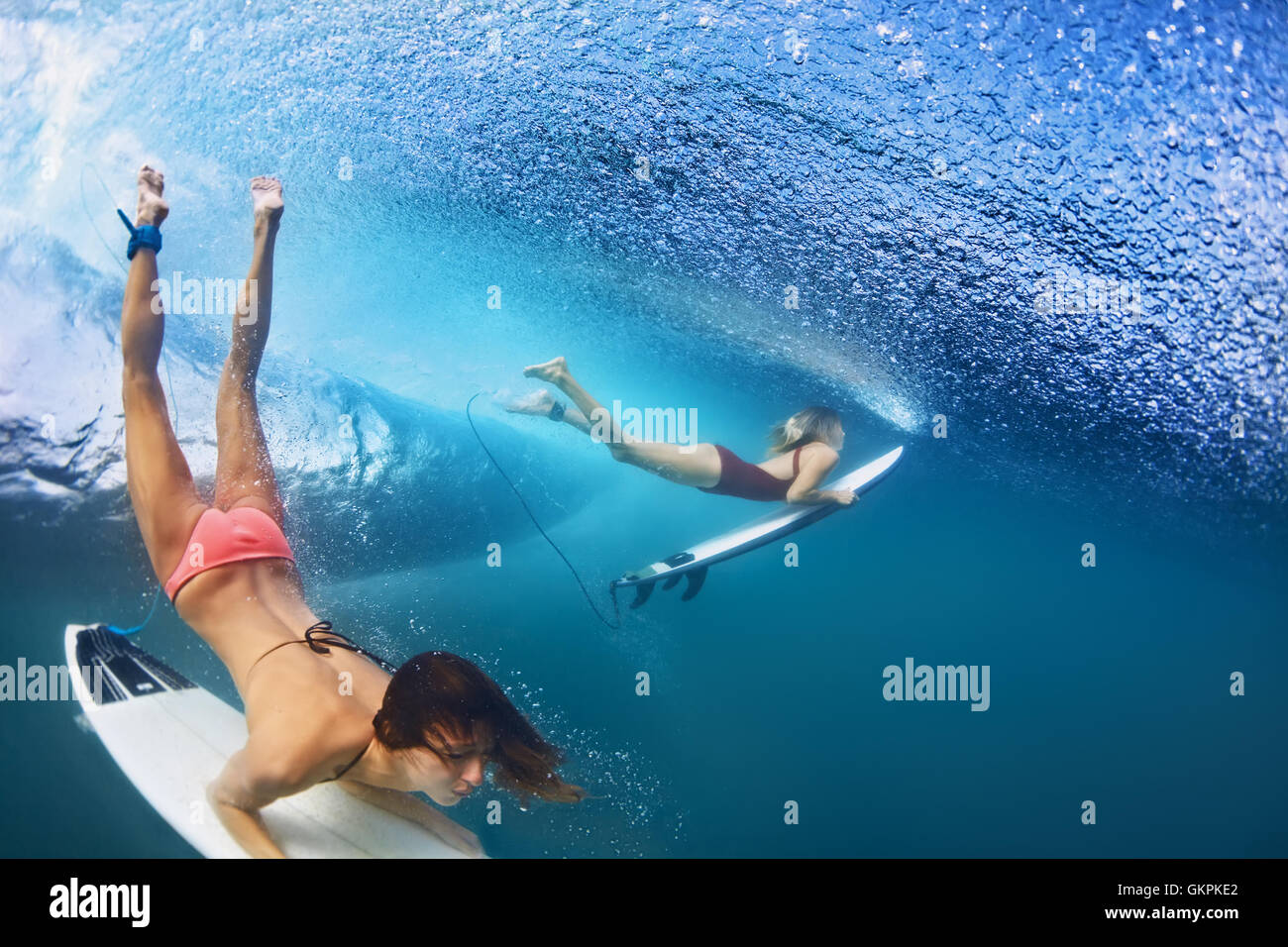 Aktive Mädchen im Bikini in Aktion - Surfer mit Surfbrett Tauchen unter Wasser unter großen Ozeanwelle zu brechen. Extreme surfen. Stockfoto