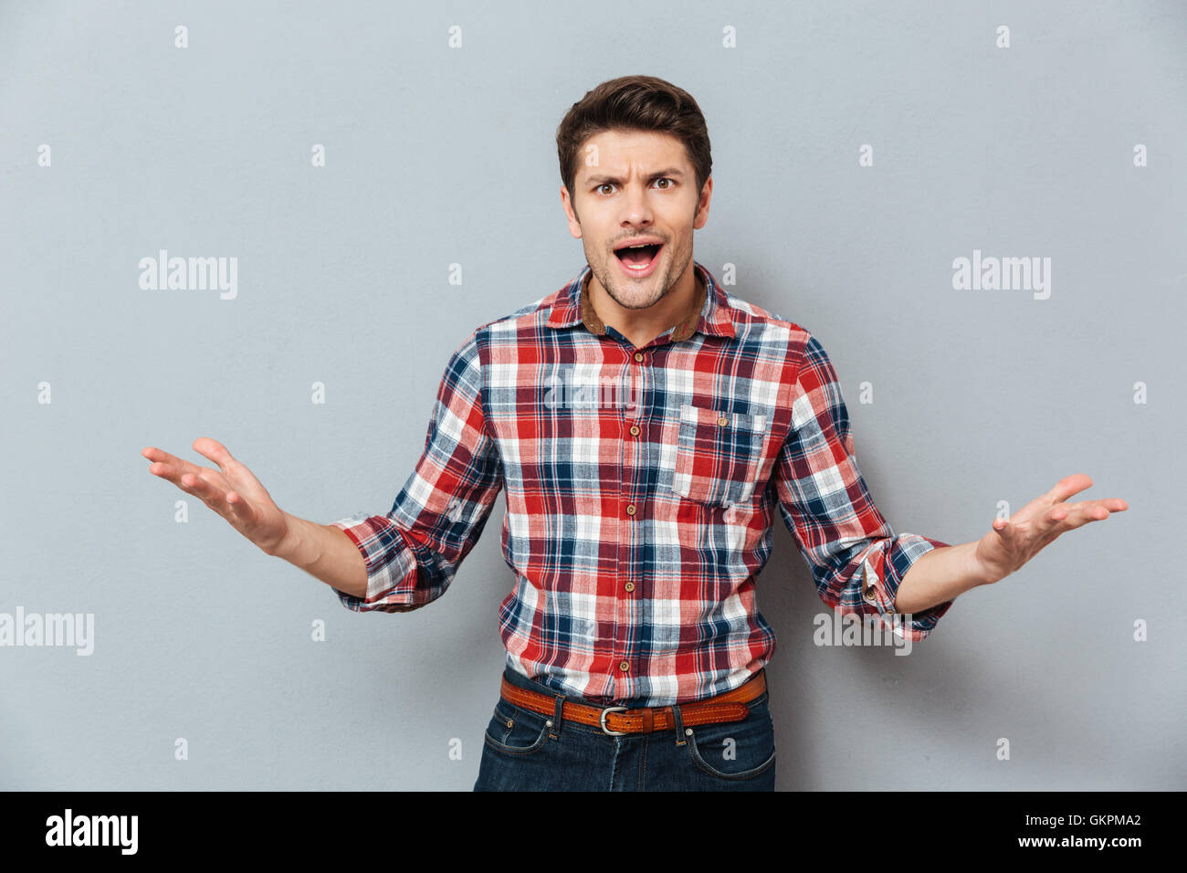 Wütend irritiert junger Mann T-shirt über grauen Hintergrund Stockfoto