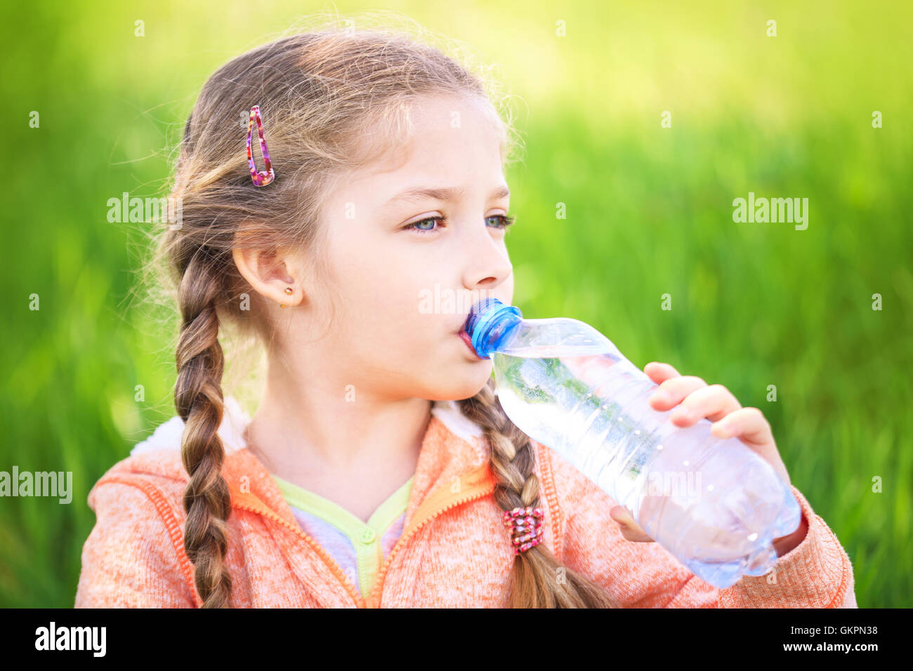 Kleine süße Mädchen über die Natur trinkt Wasser aus einer Plastikflasche Stockfoto