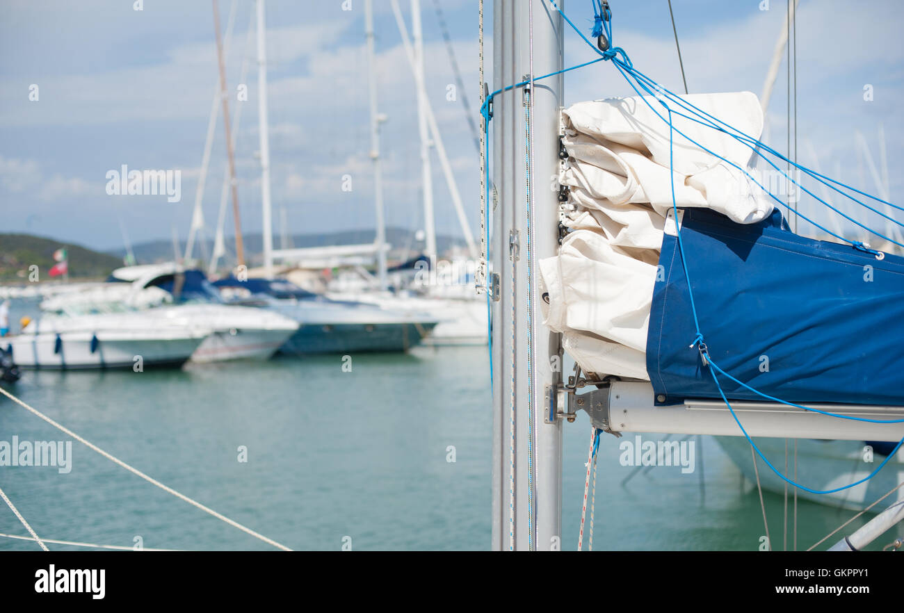 Geschlossene Segel Detail aus Fokus Hafen Pier im Hintergrund mit vielen festgemachten Segelbooten Stockfoto