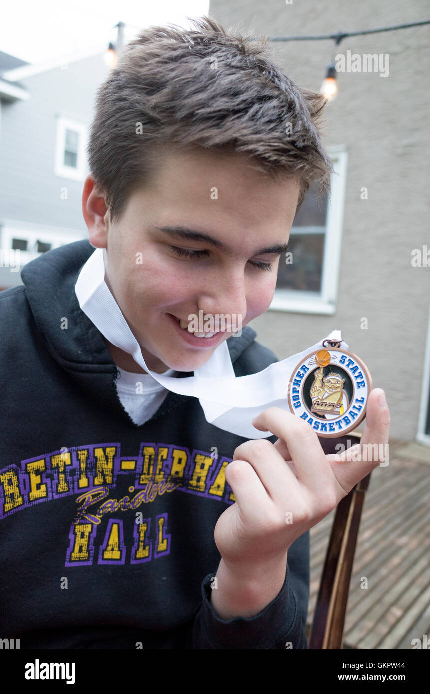 Glücklich Enkel hält seine wohlverdiente Medaille von Gopher State Basketball mit 13 Jahren. St Paul Minnesota MN USA Stockfoto