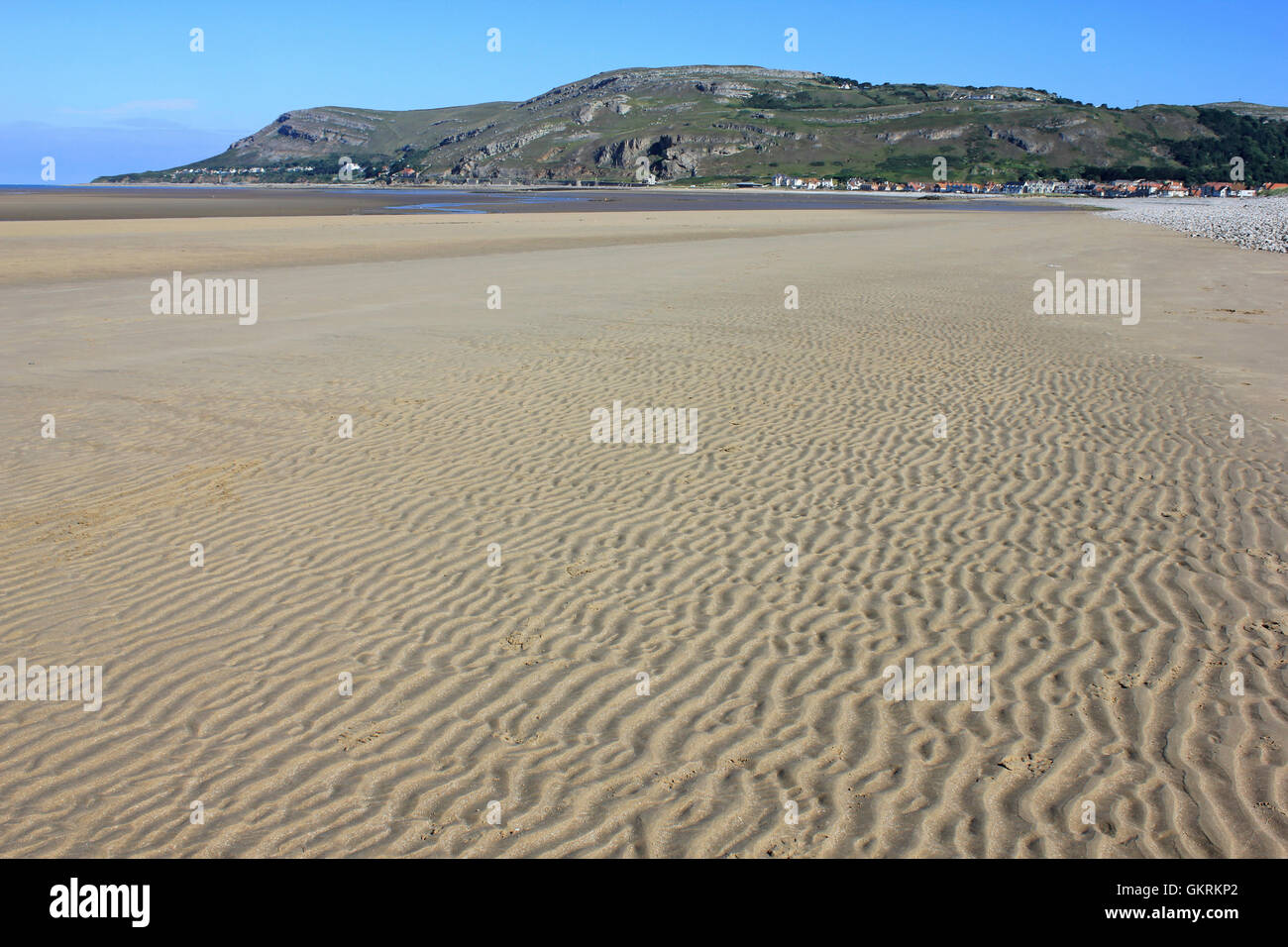 Sand, Wellen am Ufer Weststrand, Llandudno, Conwy, Wales. Großes Orme Landzunge im Abstand Stockfoto