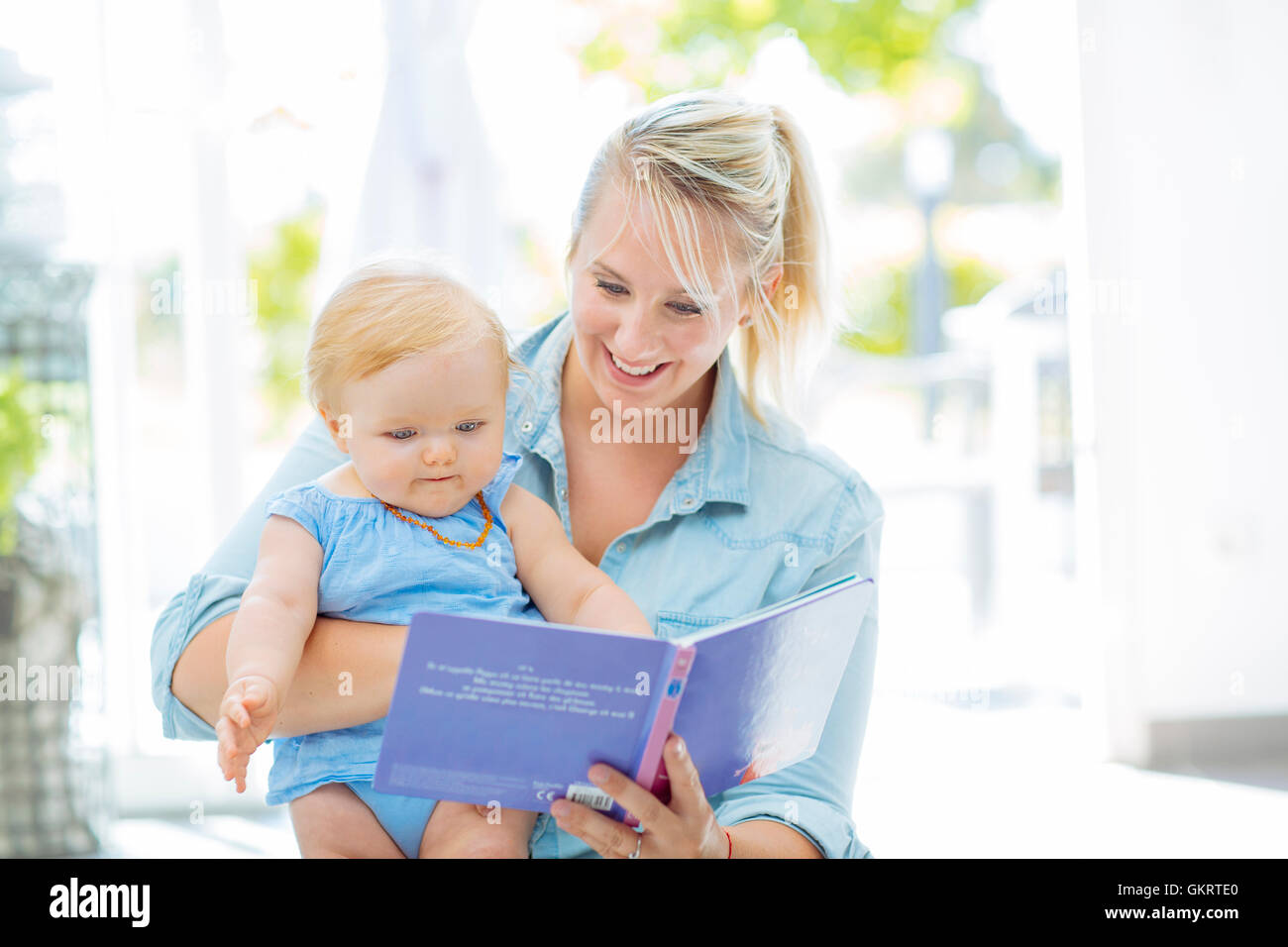 Mutter mit ihrem Babymädchen ein Buch zu lesen Stockfoto