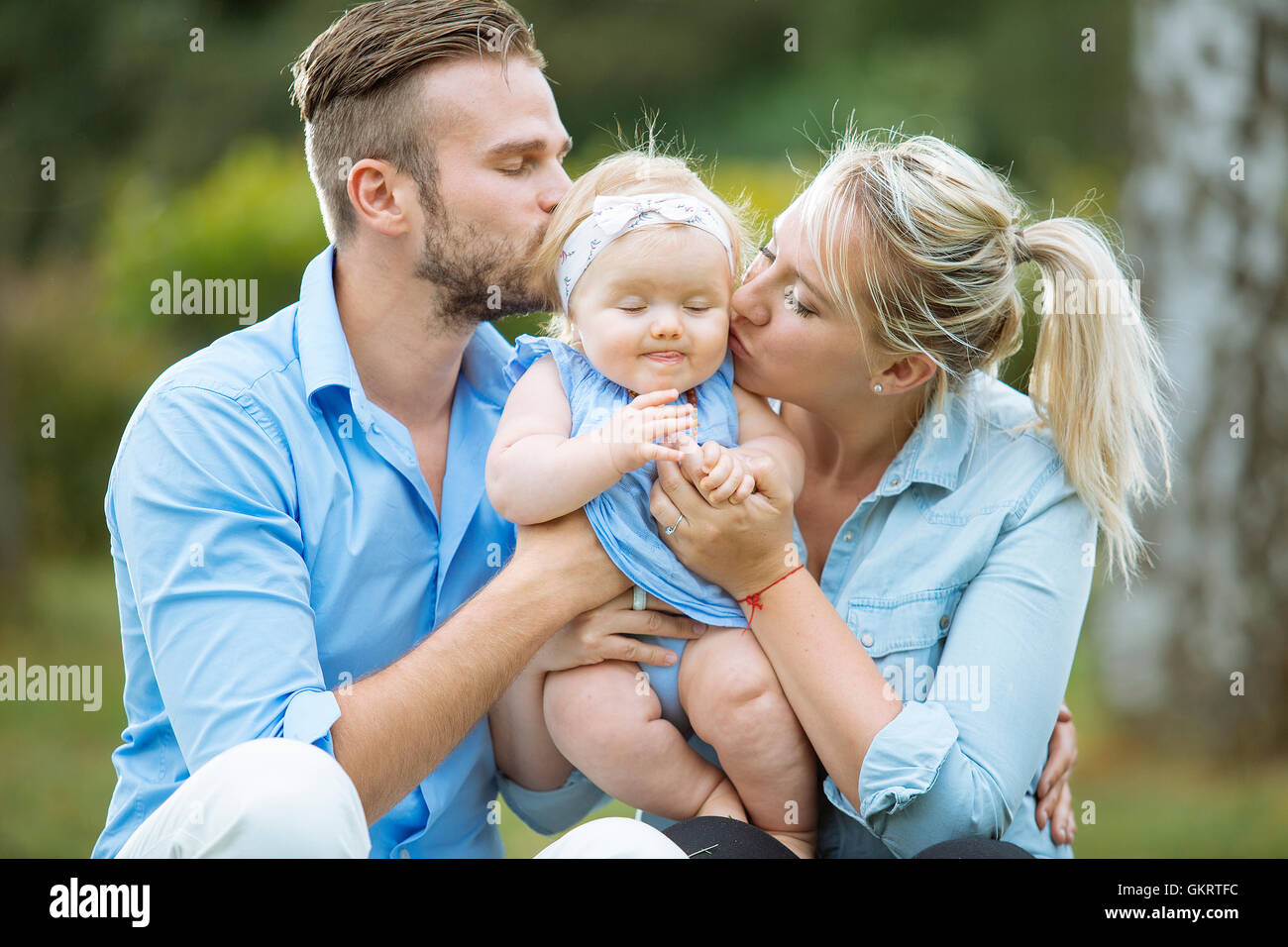 Porträt von Eltern küssen ihr Babymädchen Stockfoto