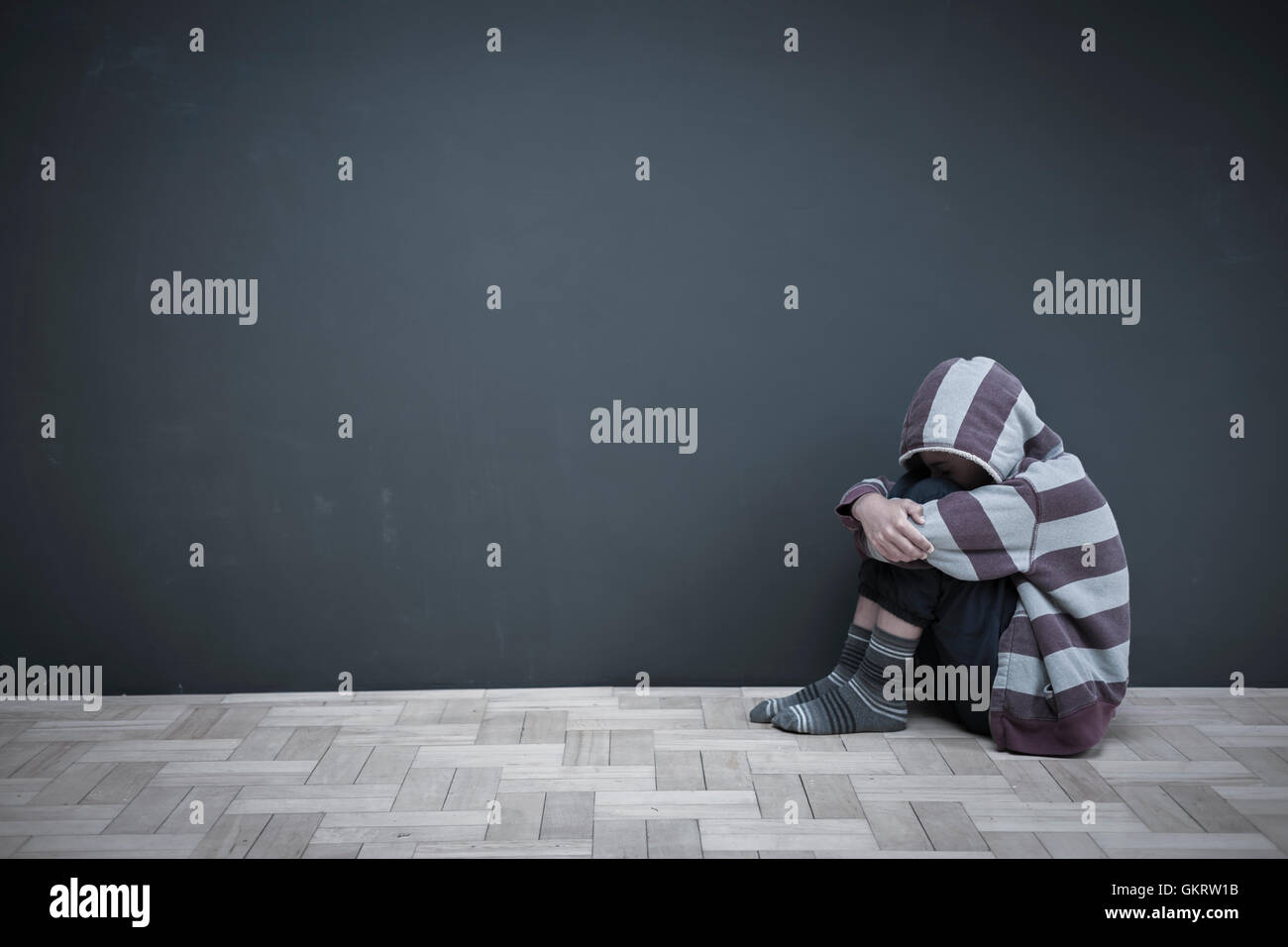 Junge am Boden knien mit Kopf nach unten zu umarmen Stockfoto