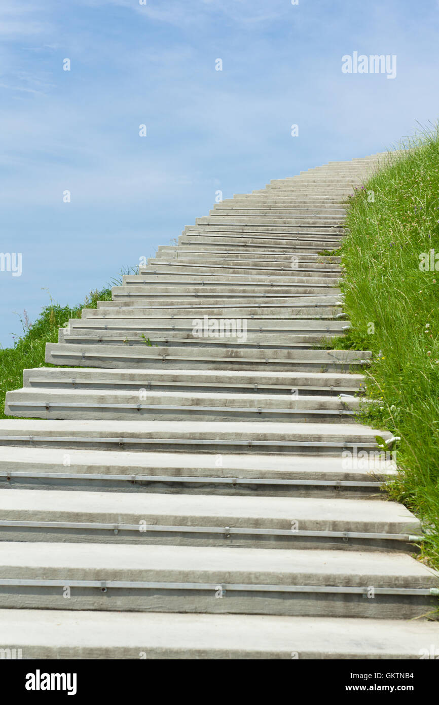 lange Treppe zum Himmel geht auf einem Hügel umgeben von Rasen Stockfoto