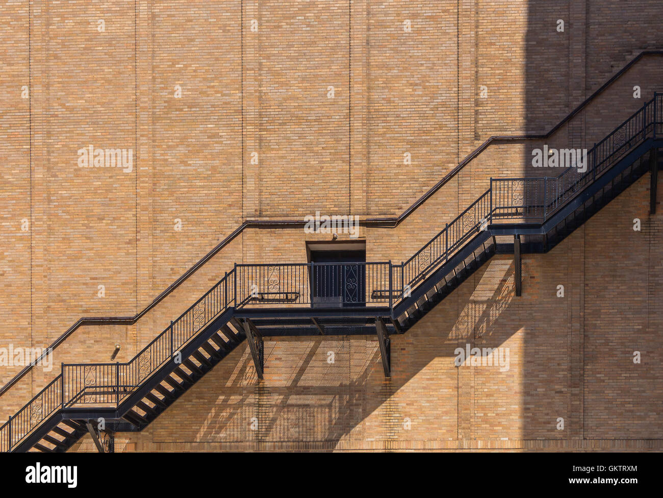 Seitenwand eines Gebäudes hergestellt aus Ziegel. Linie der Außentreppe, Tür in der Mitte. Linie von Licht und Schatten. Detroit, USA Stockfoto