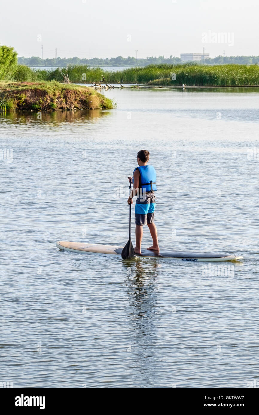 Ein 12-14 Jahre alten kaukasischen junge auf einem Stand up Paddle Board auf dem North Canadian River in Oklahoma, USA. Stockfoto