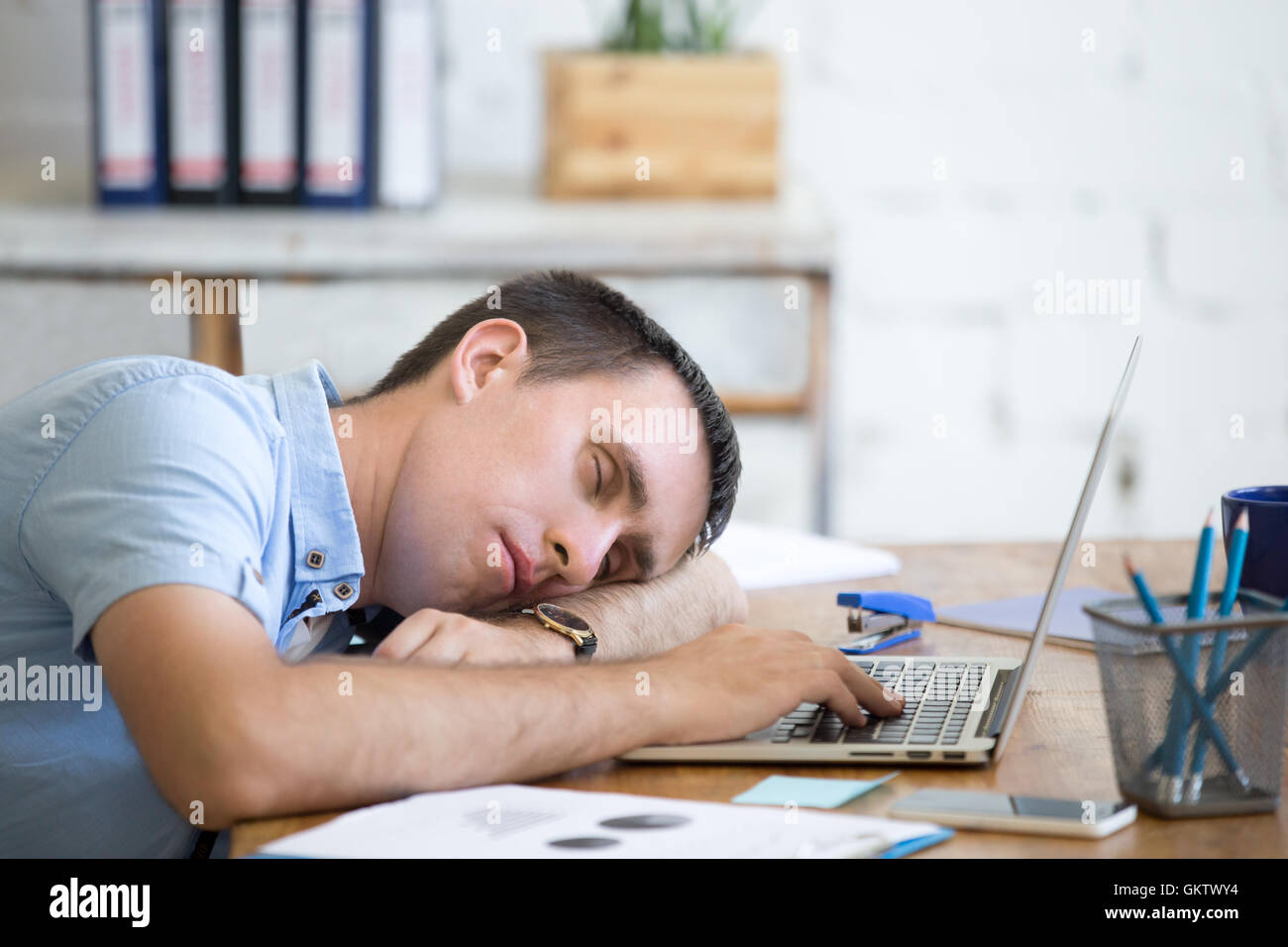 Porträt des jungen Menschen liegen auf dem Tisch vor Laptop, schläfrig, müde, überarbeitet oder faul zu arbeiten. Attraktive Business-Mann Stockfoto
