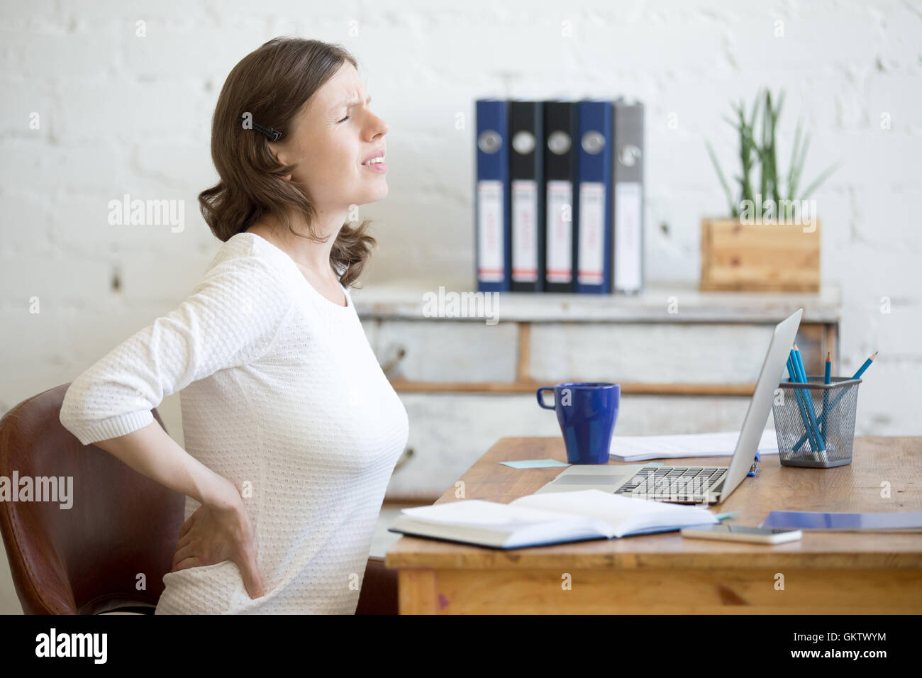 Jung betonte Geschäftsfrau vor Laptop sitzen und halten Sie ihre Taille mit gequälten Ausdruck. Business-Frau fühlen Stockfoto