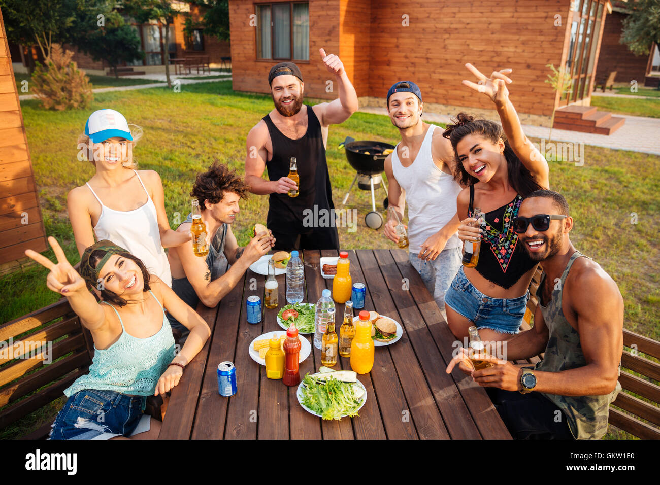 Gruppe von fröhlichen jungen Menschen Spaß und Essen am Tisch im freien Stockfoto