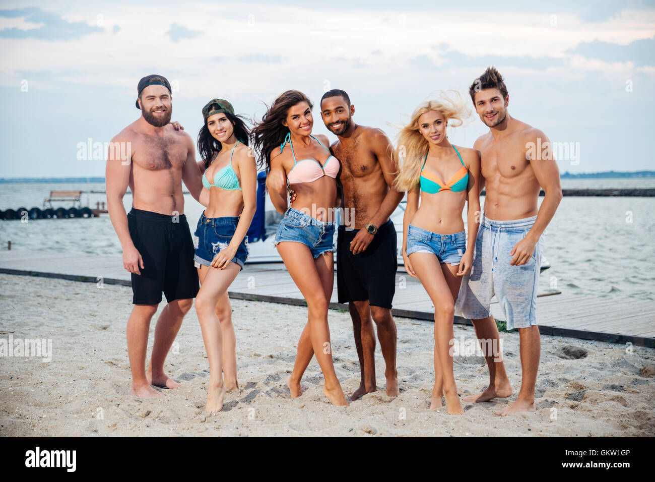 Gruppe von fröhlich glücklich jungen Freunden am Strand stehen und Lächeln Stockfoto
