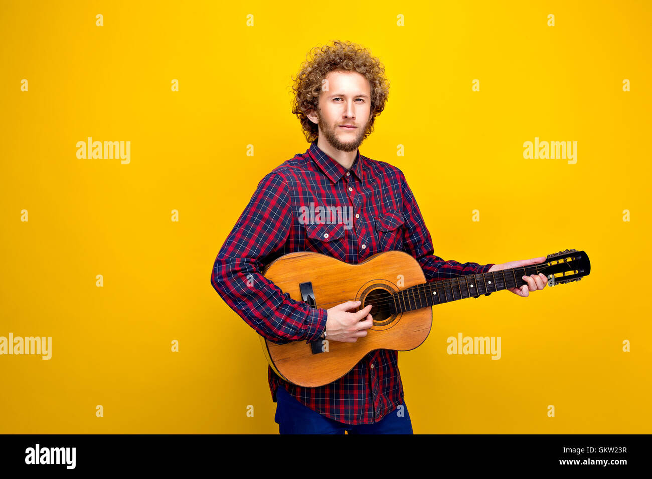 Curly-behaarte Mann in in kariertes Hemd, Gitarre spielen Stockfoto