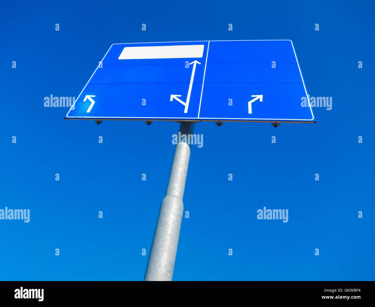 Leere blaue Wegweiser zeigen in unterschiedliche Richtungen gegen blauen Himmel Stockfoto