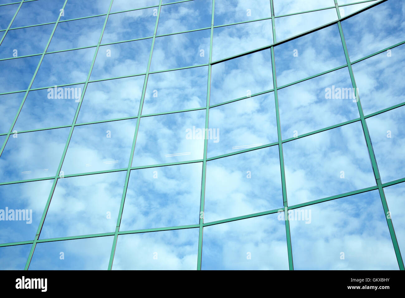 Reflexionen aus blauem Himmel und Wolken in geschwungene Fassade Stockfoto