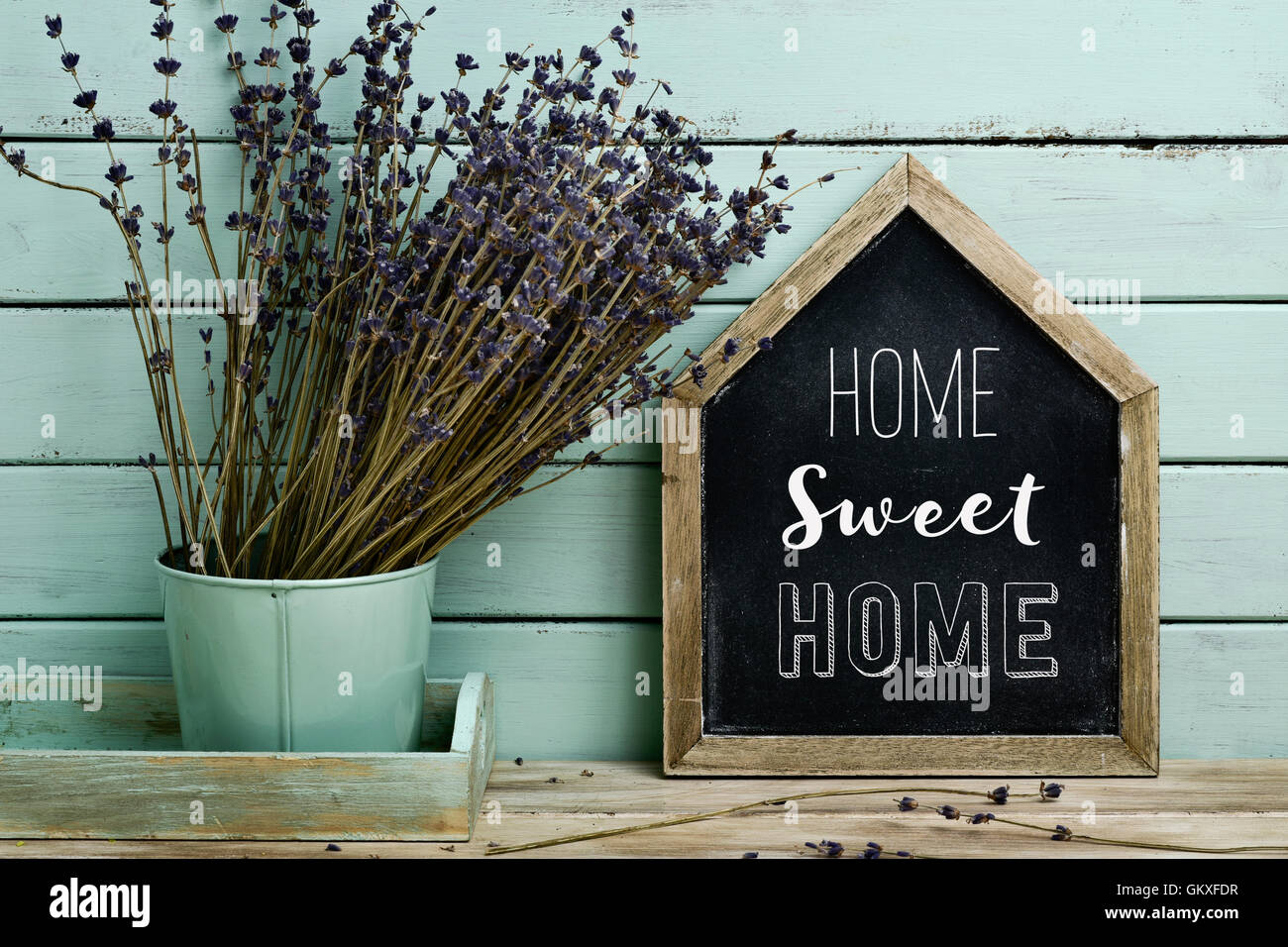 Nahaufnahme von einer Haus-förmigen Tafel mit dem Text traute Heim geschrieben und eine Handvoll Lavendelblüten in einem Blumentopf Stockfoto
