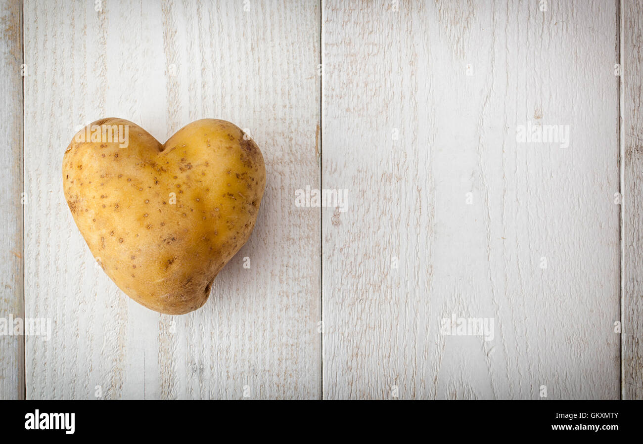 Herzförmige Kartoffeln auf weißer Holztisch. Stockfoto