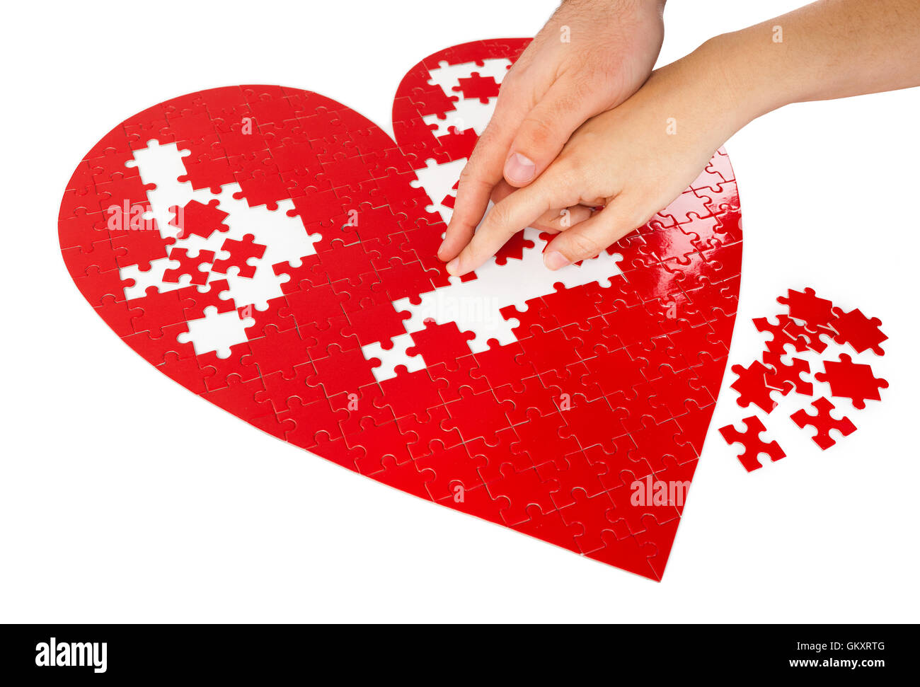 Junges Paar Montage ein rotes puzzle Herzform auf weißem Hintergrund. Stockfoto