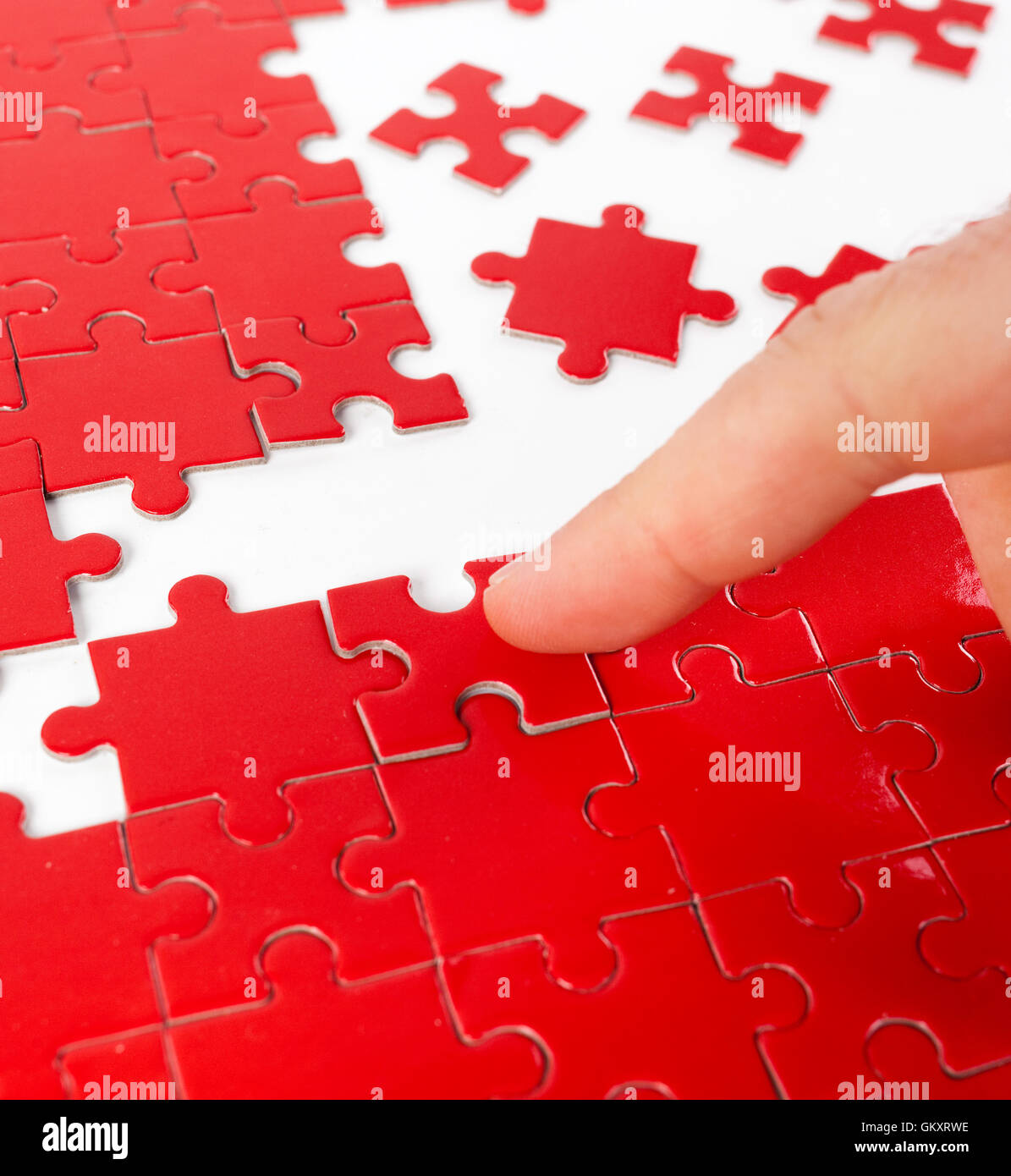 Makro eines Fingers beim greift eine rote Puzzlestück, selektiven Fokus. Stockfoto