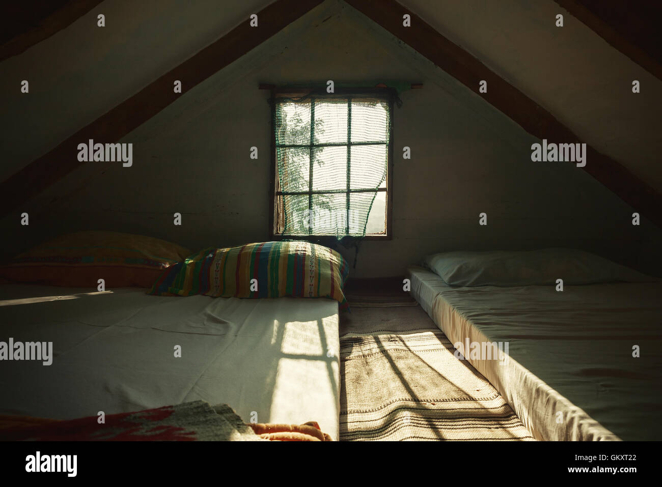 Innenansicht einer alten hölzernen Dachboden Sonnentag, verträumter ambient. Bunte Kissen hinter dem Fenster. Stockfoto