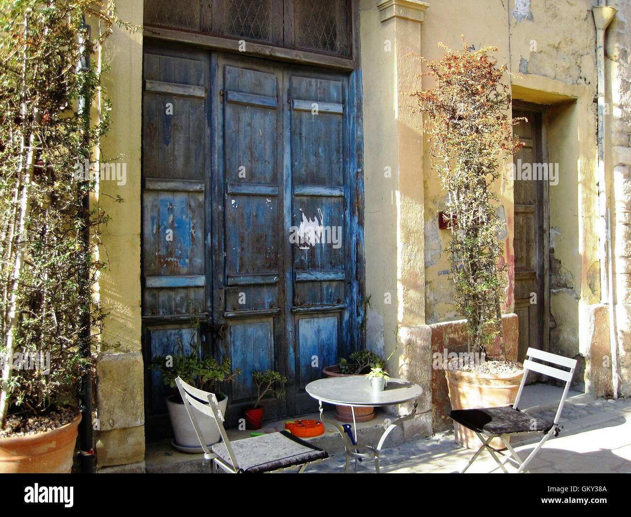 Traditionellen alten hölzernen blau zypriotischen griechischen Tür mit Kletterpflanzen, zwei Stühle und einen Tisch in der Altstadt von Limassol, Zypern. Stockfoto