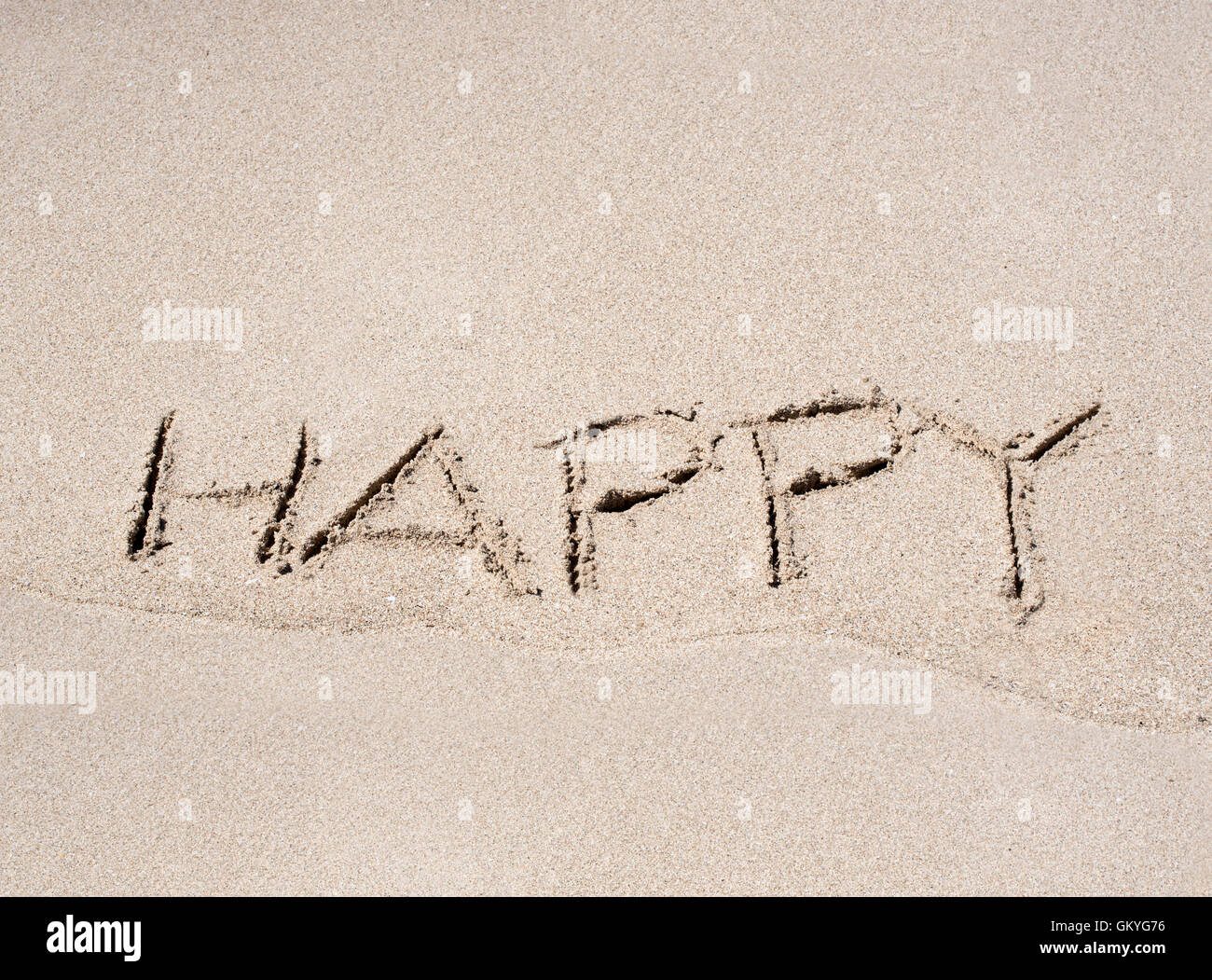 Das Wort Happy angesaugt Strandsand mit textfreiraum oben im Sommersonnenschein konzeptionelle der Saison und am Meer Urlaub Stockfoto